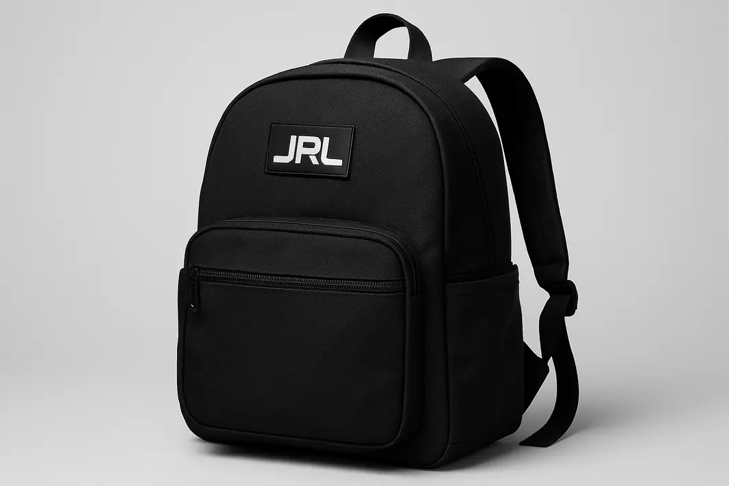 mochila jrl detalhes uso viagem Duas mochilas JRL sobre mesa de madeira com mãos ajustando alça e abrindo zíper do compartimento para laptop